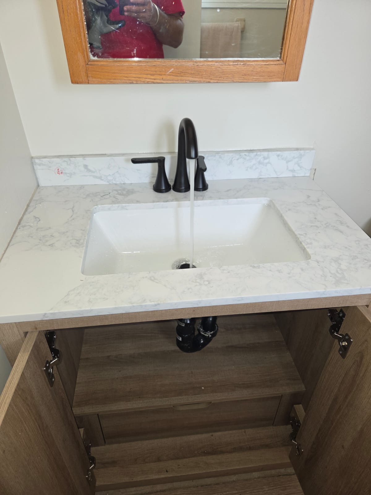 Black matte bathroom faucet running over a marble vanity sink